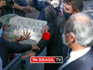 O ministro da Economia, Paulo Guedes dá dinheiro a desempregado em Brasília.