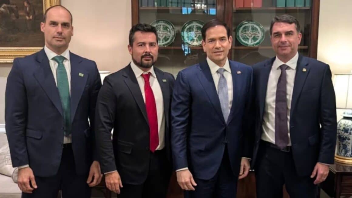 Flávio Bolsonaro dará coletiva em Miami nesta quinta (29), diz aliado Quatro homens vestidos de terno e gravata lado a lado em um ambiente formal: Eduardo Bolsonaro à esquerda, acompanhado por um aliado, o senador norte-americano Marco Rubio ao centro-direita e o senador Flávio Bolsonaro à direita.