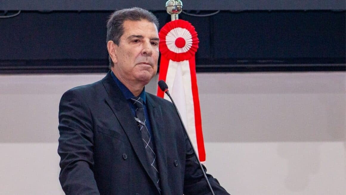 Zeca Pirão: compromisso com o desenvolvimento e a qualidade de vida no Pará O deputado estadual Zeca Pirão de terno escuro e gravata em pé na tribuna discursando ao microfone, com a bandeira do Estado do Pará ao fundo.